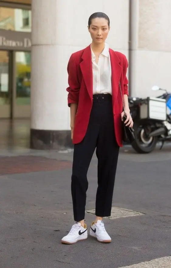pantaloni negri, un nasture alb, adidasi albi, un blazer rosu supradimensionat si o geanta neagra pentru un look casual de lucru