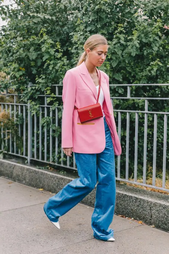 un top alb, pantaloni albastri, un blazer supradimensionat roz, pantofi albi si o geanta rosie pentru primavara