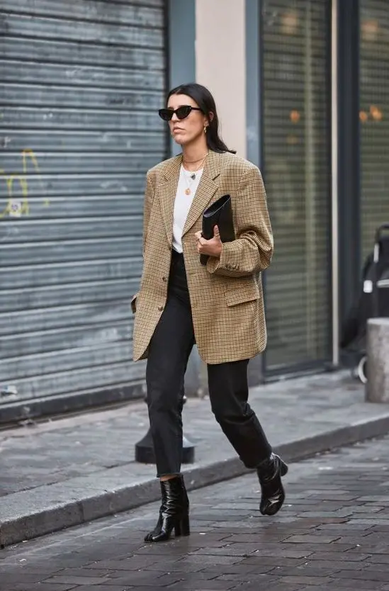 blugi negri taiati, un tricou alb, cizme negre si un blazer imprimat super supradimensionat plus un clutch